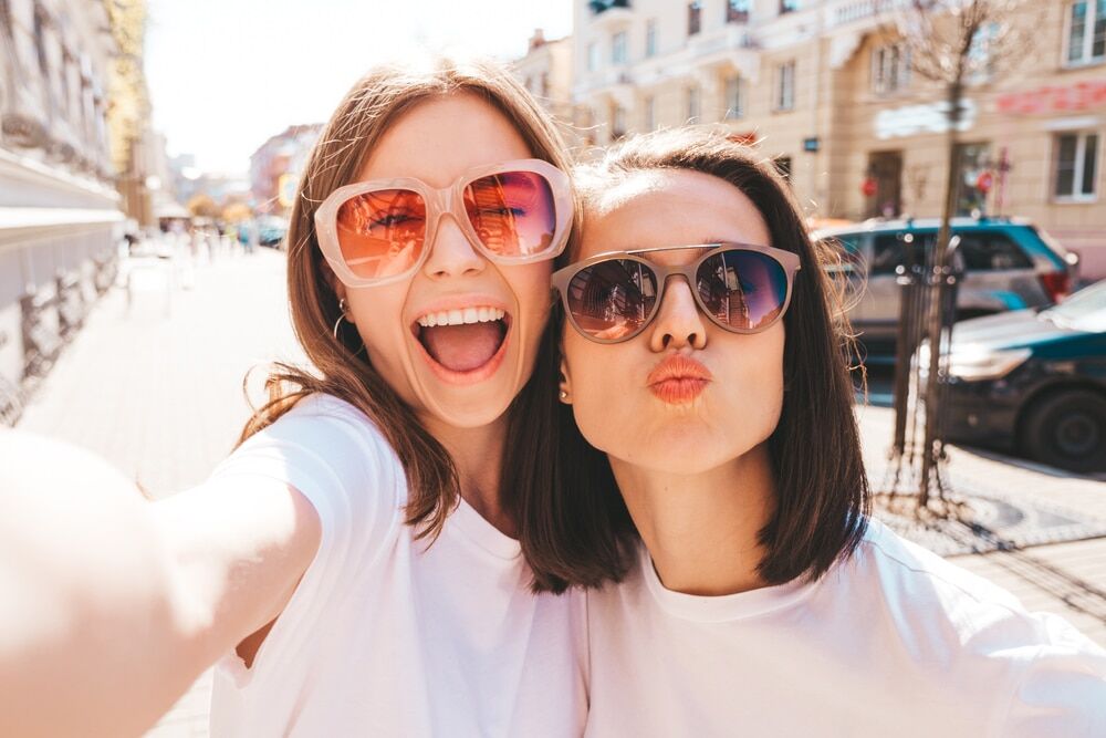 Two young women, wearing sunglasses in down town.